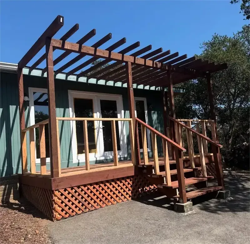 Wood deck with pergola and stairs beside a home