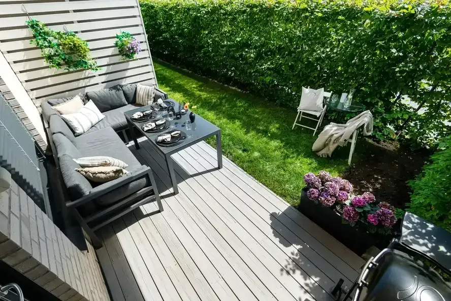 Deck lounge and dining area beside a green backyard